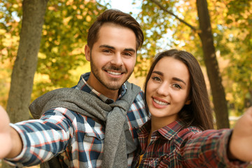 Young lovely couple taking selfie in park. Autumn walk