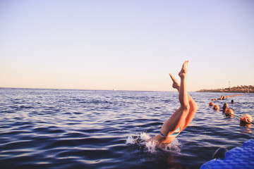 The girl in a blue bikini dives into the water. Leap in the red sea in Egypt. Red-haired woman Water splashes.