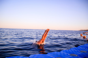 The girl in a blue bikini dives into the water. Leap in the red sea in Egypt. Red-haired woman Water splashes.