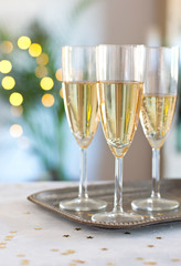 silver tray with glasses of champagne on white wooden table with lights background