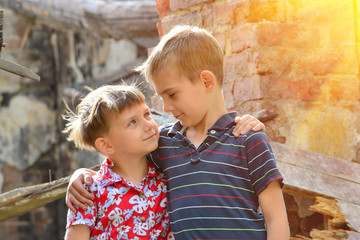 Two brothers stand near the ruined house, the concept of natural disaster, fire, and devastation.