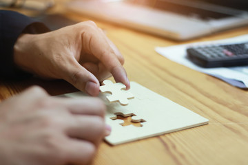 Hands of business people hold paper jigsaw puzzle.Business team assembling