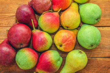 Red, green and yellow colorful ripe pears on a wooden table. Summer fruit harvest. 