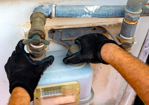 Worker removes the seals to the fitting between the pipe and gas meter. Selective focus