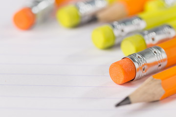pencils with an eraser on the back side lie on a notebook sheet in a strip