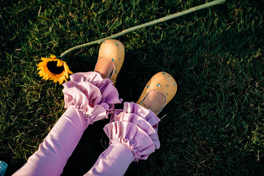Child's legs on grass with sunflower nearby