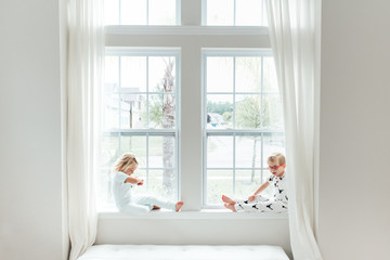 Two children sitting on a window sill