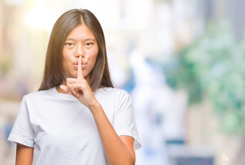 Young asian woman over isolated background asking to be quiet with finger on lips. Silence and secret concept.