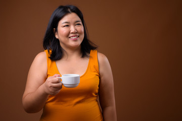 Beautiful overweight Asian woman holding coffee cup