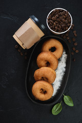 Donuts with takeaway coffee, top view on a black stone background, vertical shot