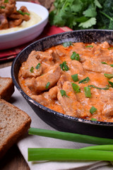 Pieces of meat stewed in tomato and sour cream sauce in the frying pan