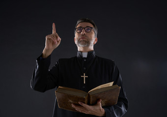 Priest holding bible pointing finger up