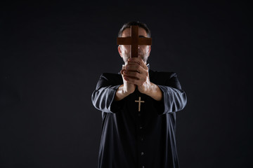 Priest holding cross of wood praying