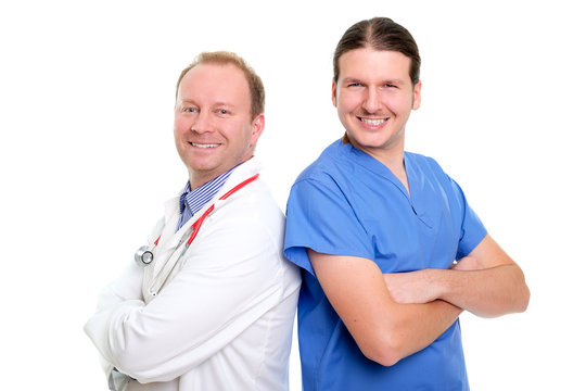 Portraits Of Smiling And Happy Friendly Doctors Team Standing With Arms Folded, Middle Age Man And Young Man In White And Blue Uniform, Isolated On White Background. Healthcare Concept