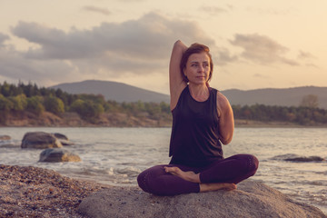 Fototapeta premium Woman practicing yoga on the beach at sunset.