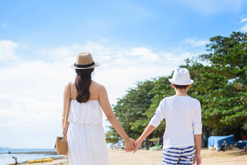  happy family mother with boy walks holding hand on the beach ,white sand beach  ,look happy in the summer