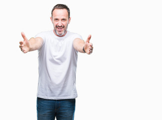 Middle age hoary senior man wearing white t-shirt over isolated background looking at the camera smiling with open arms for hug. Cheerful expression embracing happiness.
