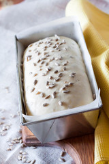 Raw yeast dough in tin form, ready for baking bread with sunflower seeds