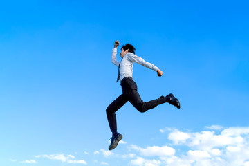 Fototapeta na wymiar 青空をバックにジャンプするYシャツ姿の若いビジネスマン1人。元気・パワー・喜び・挑戦イメージ