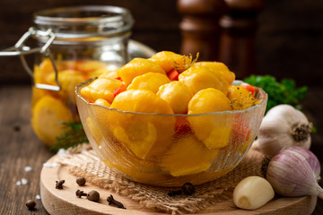 Marinated pattypan squash in glass bowl on dark rustic wooden background. Selective focus.