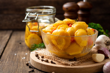 Marinated pattypan squash in glass bowl on dark rustic wooden background. Selective focus.