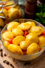 Marinated pattypan squash in glass bowl on dark rustic wooden background. Selective focus.