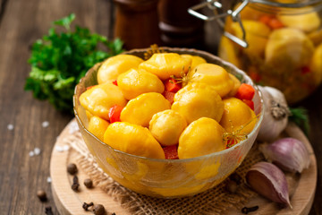 Marinated pattypan squash in glass bowl on dark rustic wooden background. Selective focus.