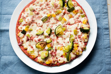 Beetroot base pizza with zucchini, smoked ham, cheese & red onion