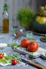 Baked tomatoes with spices and herbs on a gray background. Vegetarian menu