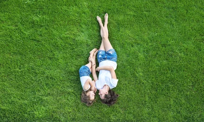 Gartenposter Conceptual portrait of a mother relaxing with daughter on a fresh, green lawn © konradbak