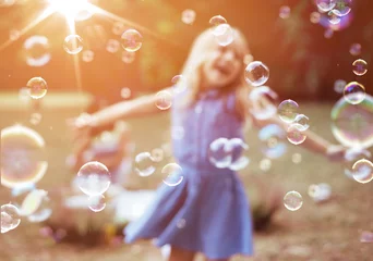 Wandaufkleber Fröhliches kleines Mädchen, das das Blasen genießt © konradbak