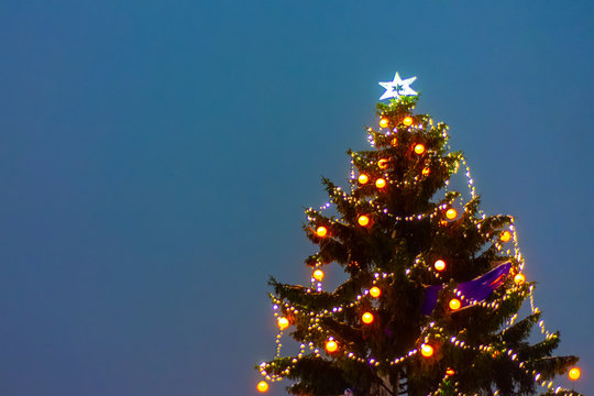 Illuminated christmas tree at night with falling snow and copy space