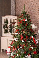 Fototapeta na wymiar Christmas tree with colorful balls and gift boxes over brick wall. New Year Christmas concept.
