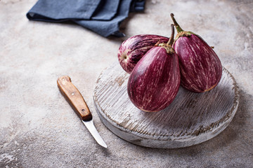 Fresh striped purple aubergines on light background