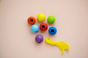 Developmental children's toy. Colored wooden balls on a rope. Colorful wooden baby beads for necklace.