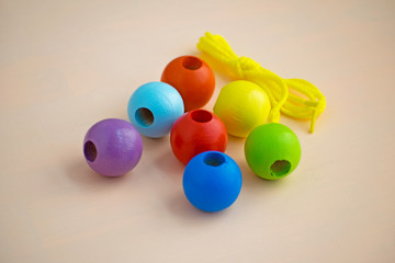 Developmental children's toy. Colored wooden balls on a rope. Colorful wooden baby beads for necklace.