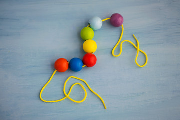 Developmental children's toy. Colored wooden balls on a rope. Colorful wooden baby beads for necklace.
