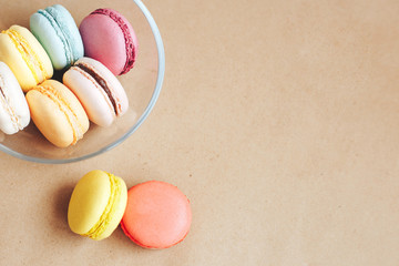 transparent bowl with multi-colored macaroons on kraft brown background