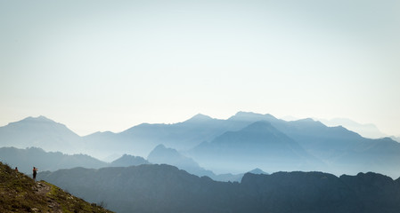 Hiker looking at the Cantabrian mountain range surrounded by haze on a sunny summer morning