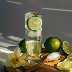 a glass of water with lime on a wooden board and a narcissus