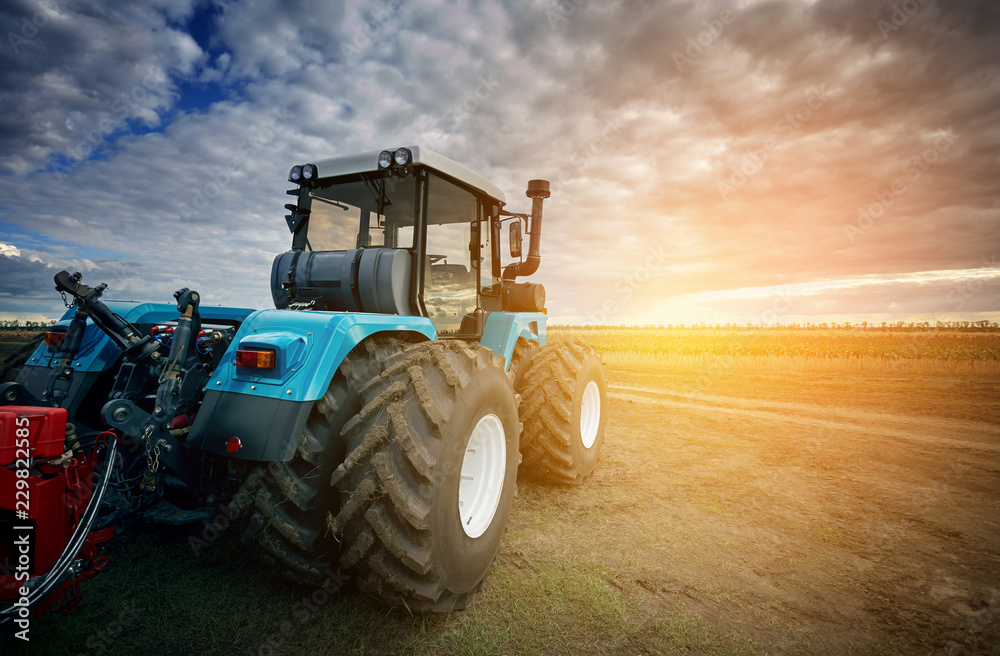 Aufkleber tractor working in the field in the background of the sunset