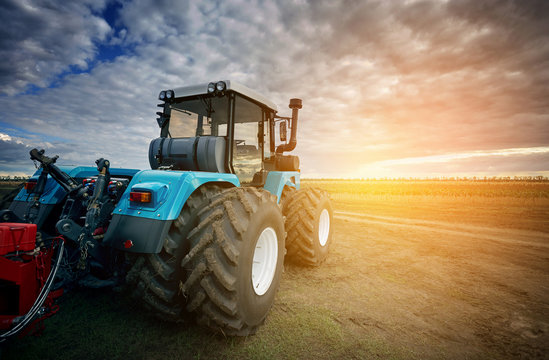 Tractor working in the field in the background of the sunset