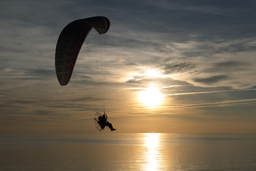Paraglider over the sea at sunset.