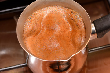 the beginning to boil coffee in the Turk on a plate, the top view