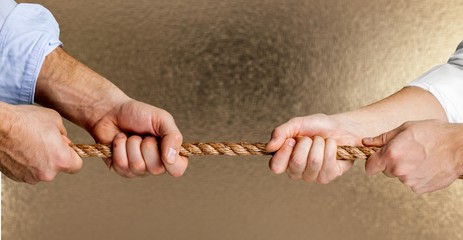 Business people pulling rope in opposite directions at office