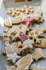 Painted traditional Christmas gingerbreads arranged on wooden tray in daylight, lots of Xmas symbols, red color