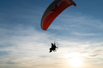 Paraglider over the sea at sunset.