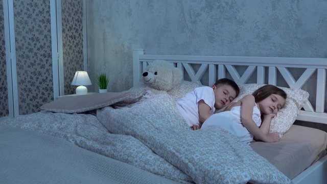Two children lie on the bed and sleep