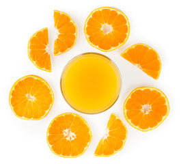 Orange juice in a glass Cup and pieces laid out around on a white. The view from the top.