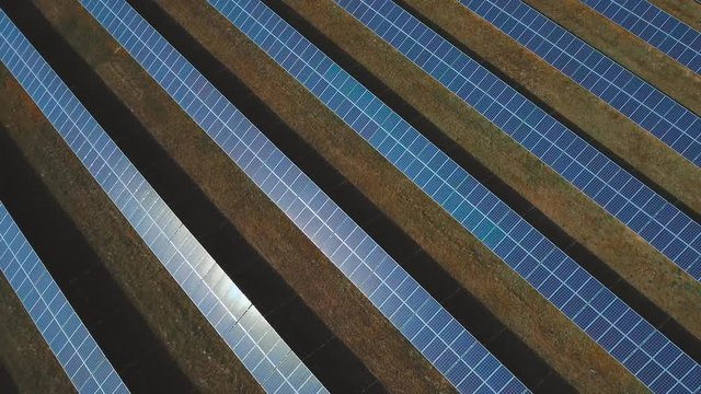 Many solar panels planted on the field. Shot on drone